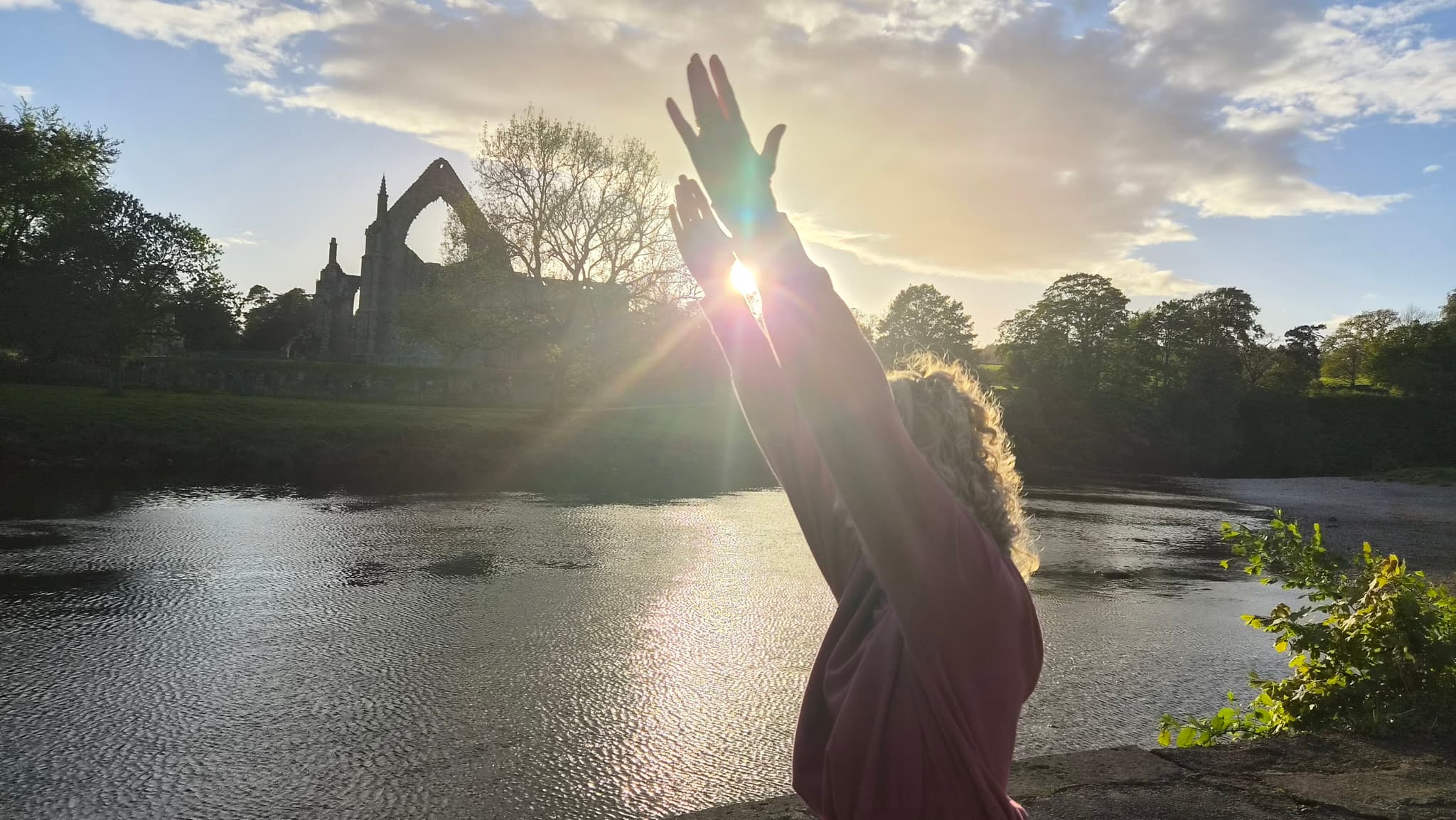 Hands reaching towards the evening sun by the water
