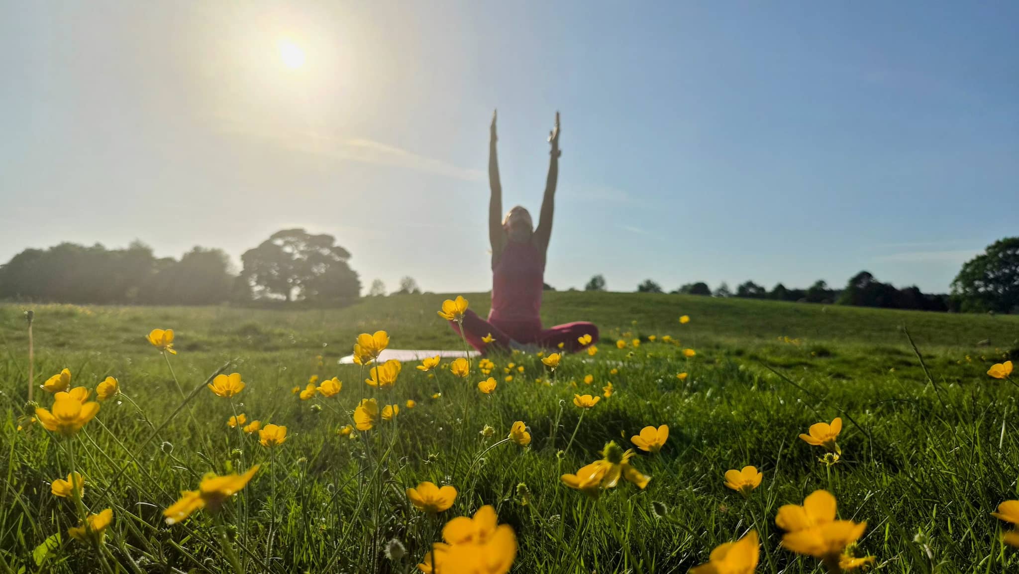 Victoria practising yoga in a buttercup meadow near Skipton at golden hour